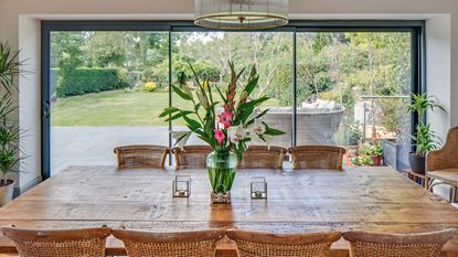 Wooden dining table in front of three panelled sliding glass doors