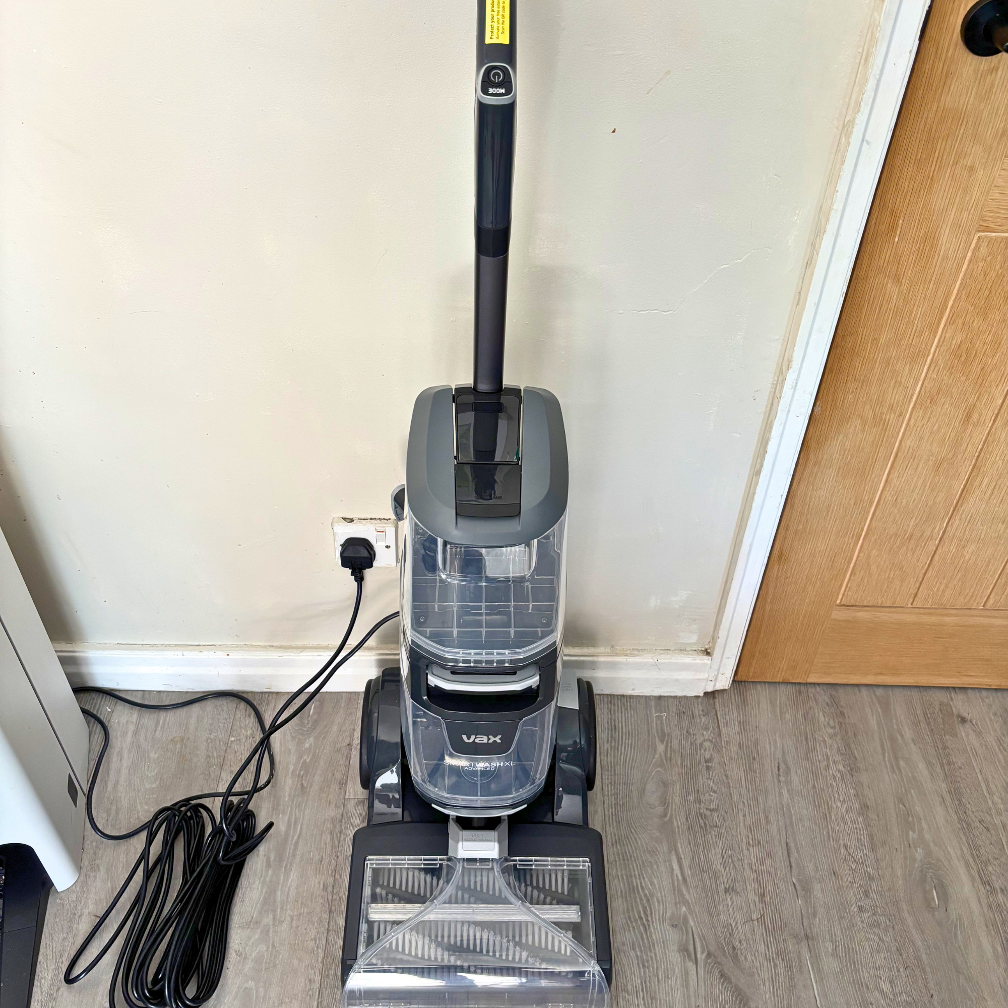 VAX Platinum SmartWash plugged into mains, positioned against a wall