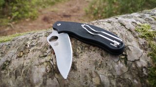 Spyderco UK Penknife Drop Point (UKPK) camping knife partially folded on log