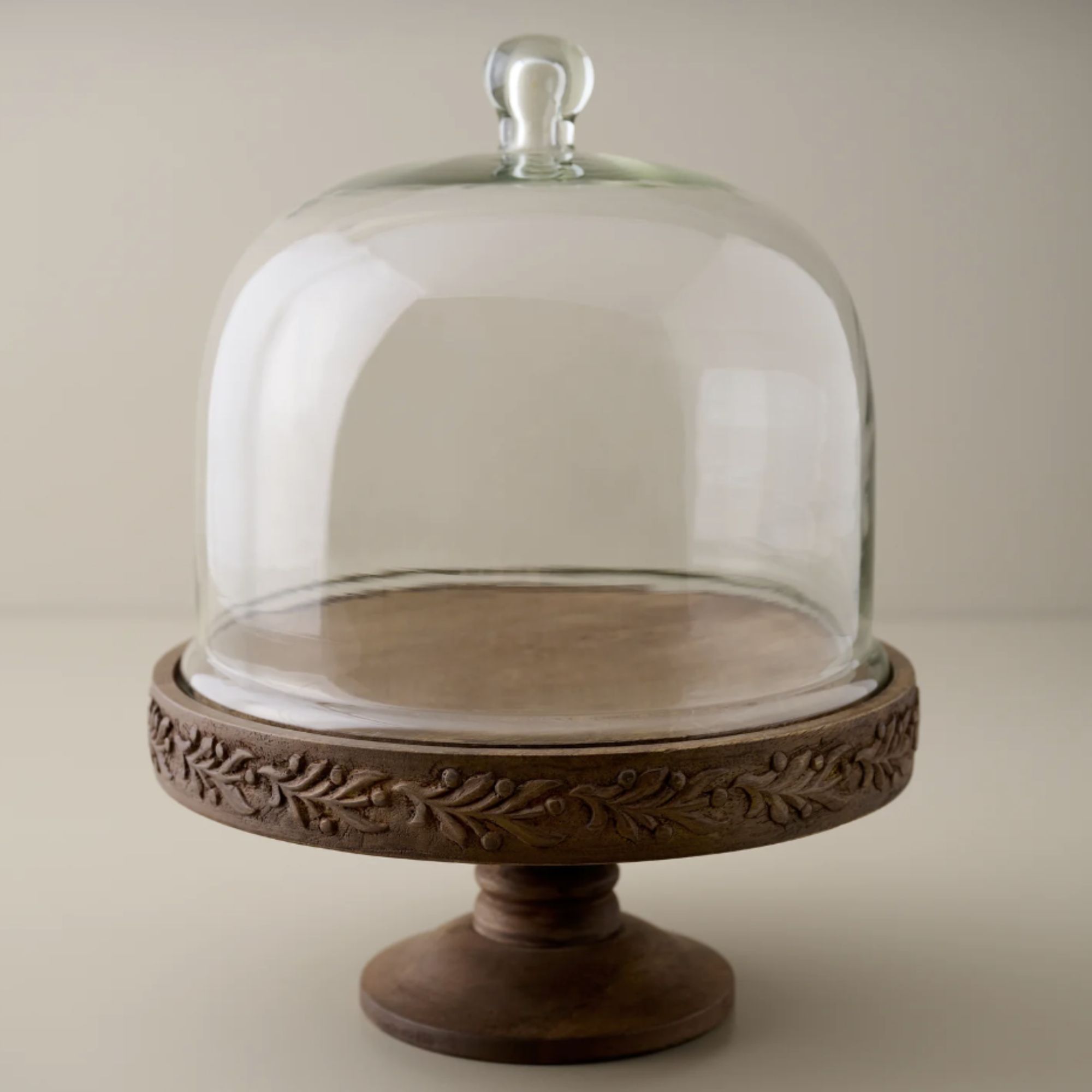 Carved wood cake stand with tall glass dome
