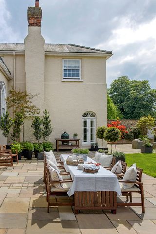 patio with wooden tables and chairs outside large georgian property
