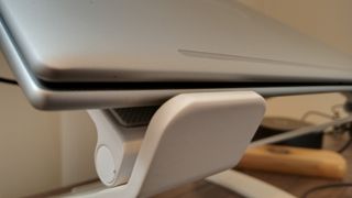 A white z-type Curve Flex laptop stand on a brown desk