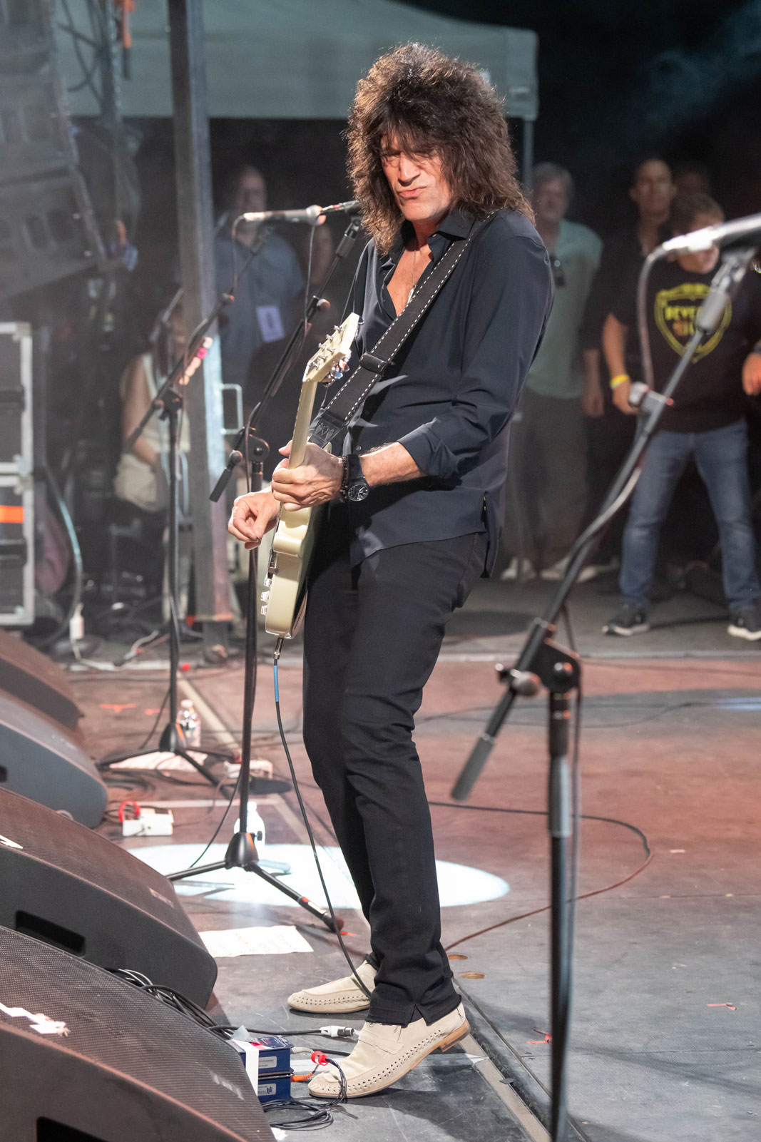 Tommy Thayer performs onstage holding a white Gibson Les Paul