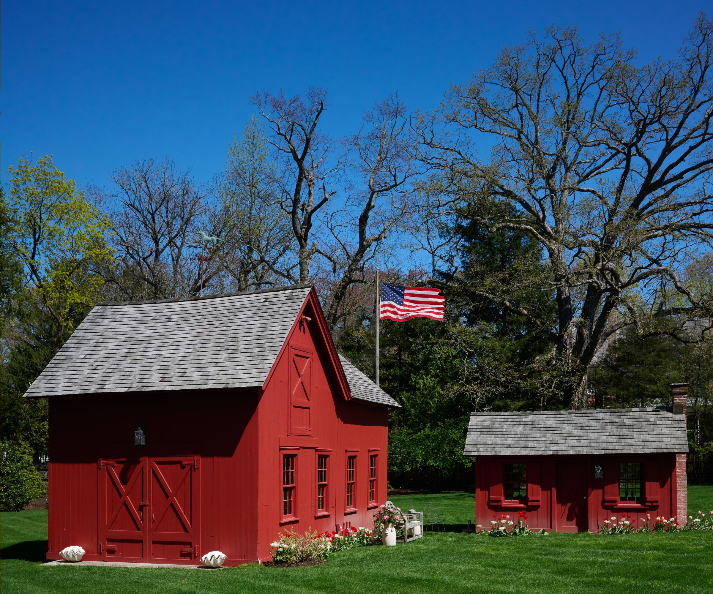 Two red barns in a field with the American flag