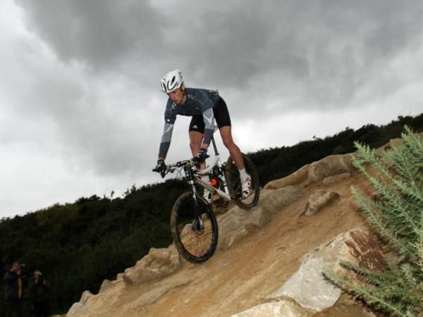 Cannondale rider Paul Beales demonstrates one of the man-made features on the Olympic mountain bike course at Hadleigh Farm in Essex