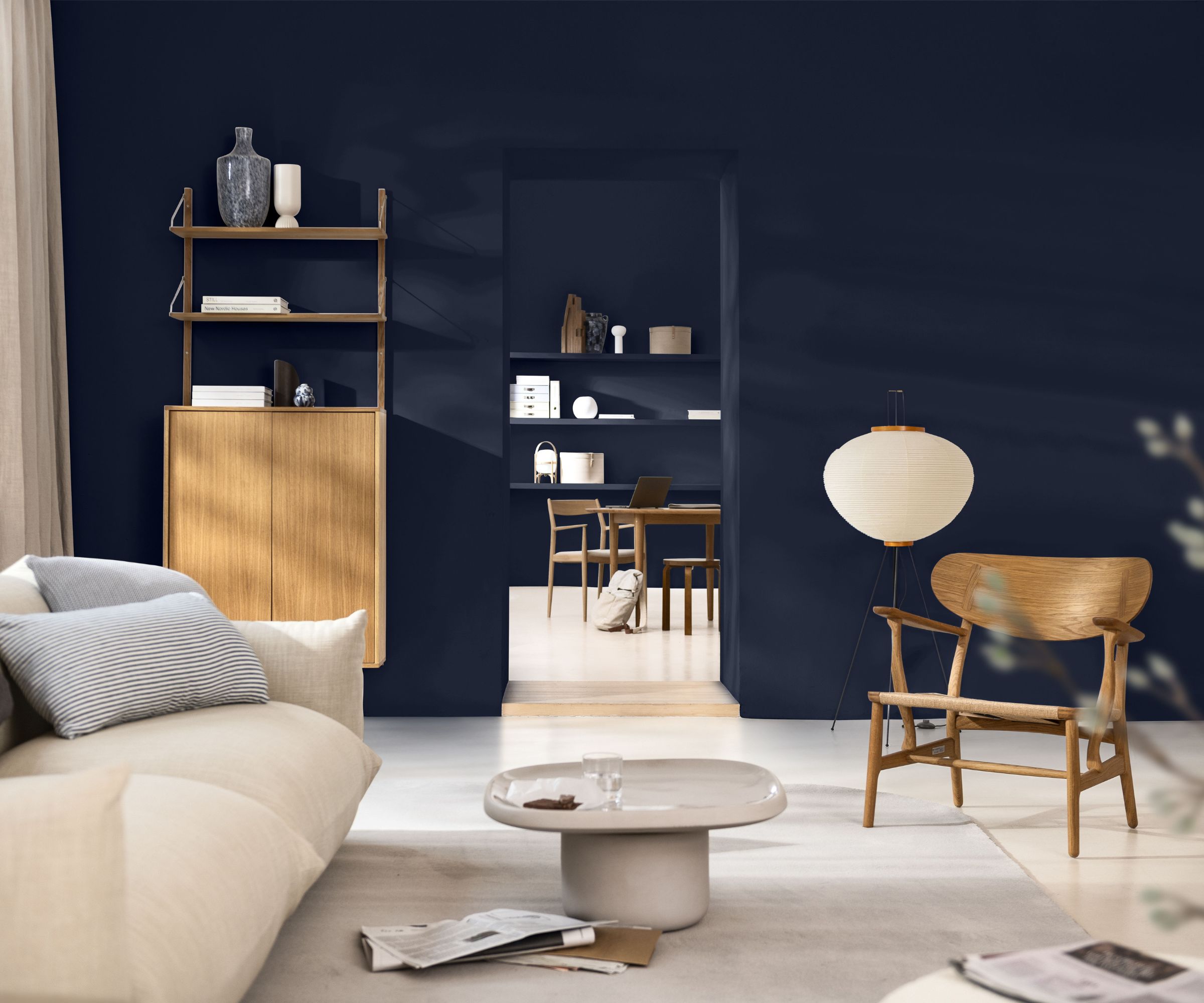 Living room with navy blue walls, modern furniture, cream sofa, low cream coffee table and wood bookshelf