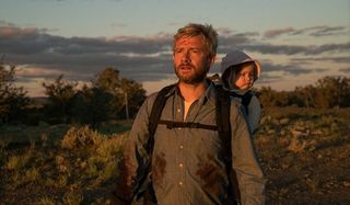 Cargo Martin Freeman carrying his baby in the sunset