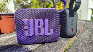 JBL Go 4 Bluetooth speakers on wooden outdoor table showing different colourways