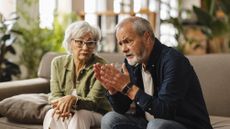 An older couple have a serious discussion on their sofa.