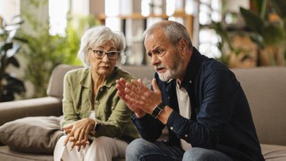 An older couple have a serious discussion on their sofa.