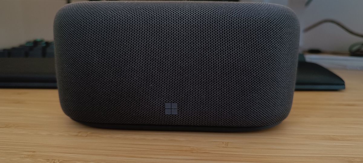 A grey Microsoft Audio Dock sitting on a wooden desk