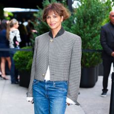 Halle Berry wears low-rise puddle jeans with heels and a single-breasted jacket at a Chanel event in New York.