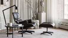 scandinavian interior with gray rug, eames chair and ottoman, side table with book and decor, arched floor lamp, curtain against wall and big windows