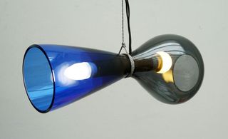 Contemporary designed blue and black ceiling light with bulbs on., photographed against a grey background