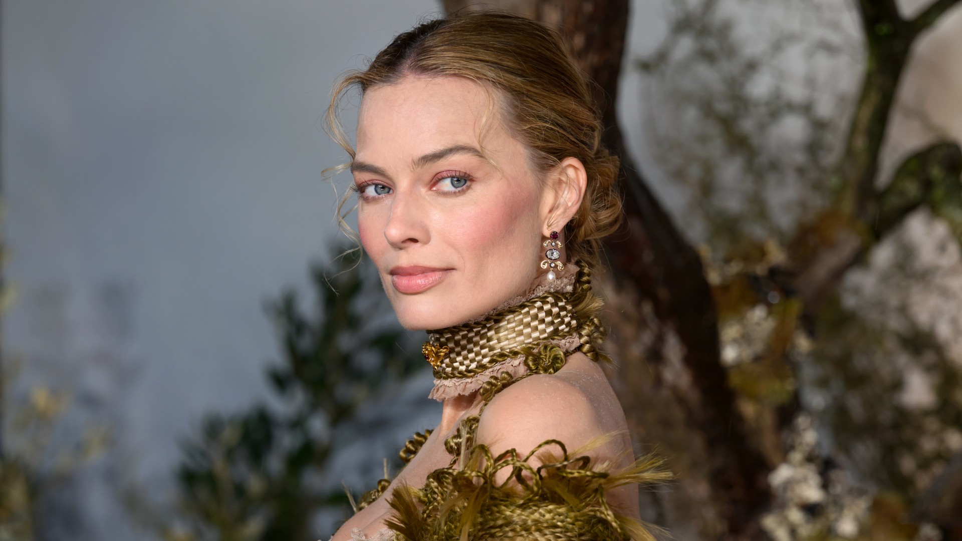a white woman posing in front of a floral background at a movie premiere