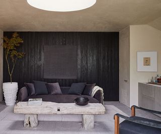 bar with grey sofa and black charred wood walls and curved concrete bar