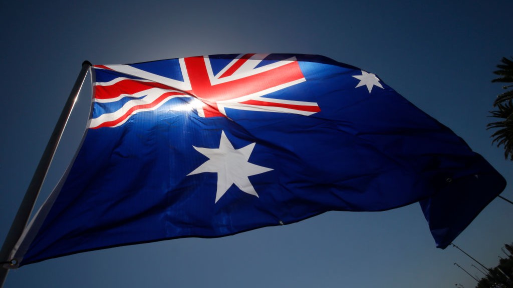 Australia flag moving in the wind, sun behind