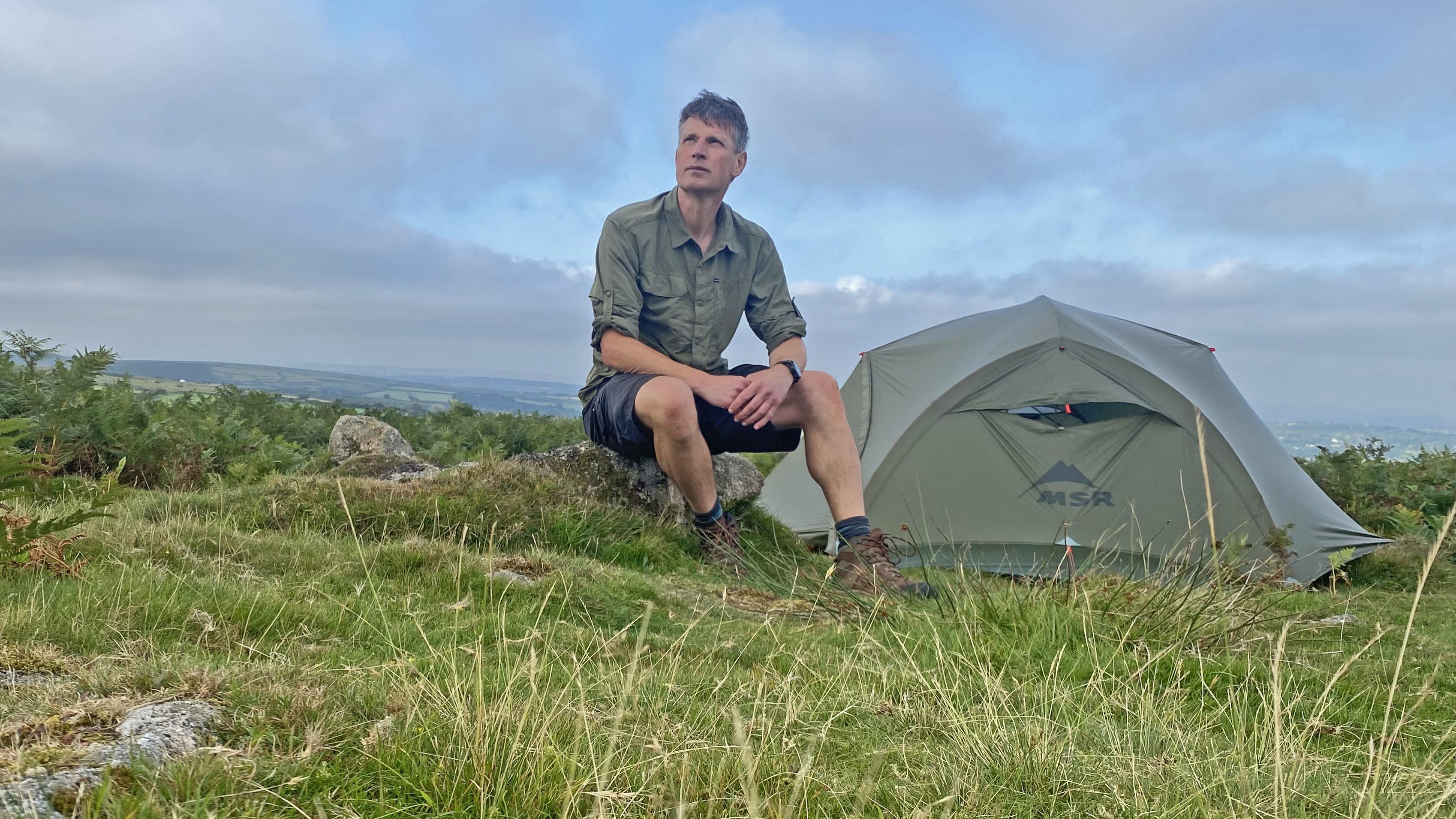 Man wearing the Columbia Skien Valley Shirt beside a tent