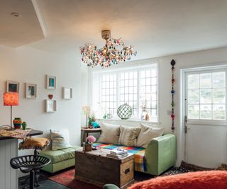 Cozy living room with green sofa, multicolored throw, wooden chest coffee table and multicolored ceiling lights