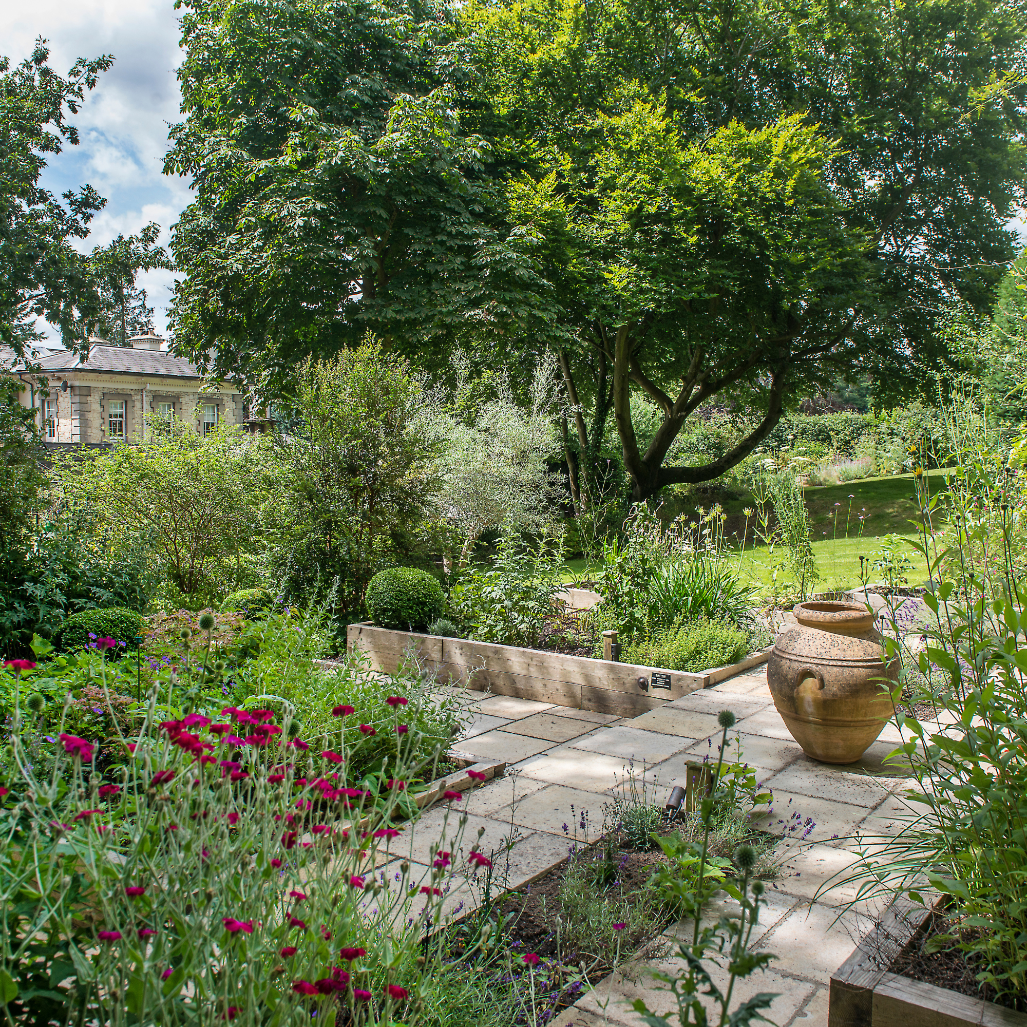 An early Victorian home in Sussex, home of Clare Clarke and husband David, exterior view of the garden with a paved garden path.