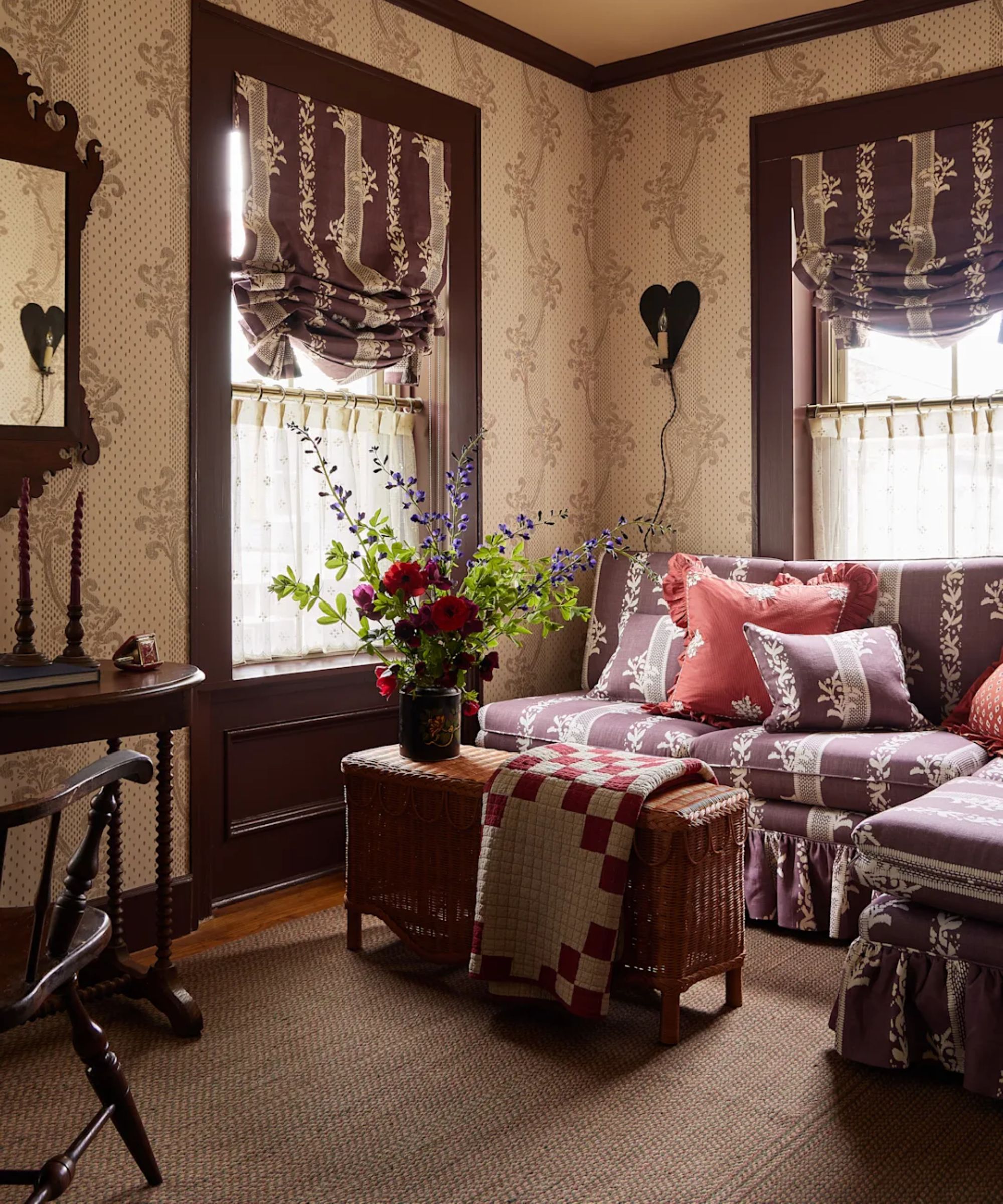 floral purple living room set up at the six bells inn hotel with a rattan ottoman with a quilt and a cozy floral banquette skirted couch