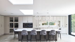 large white kitchen with large kitchen island and roof lantern