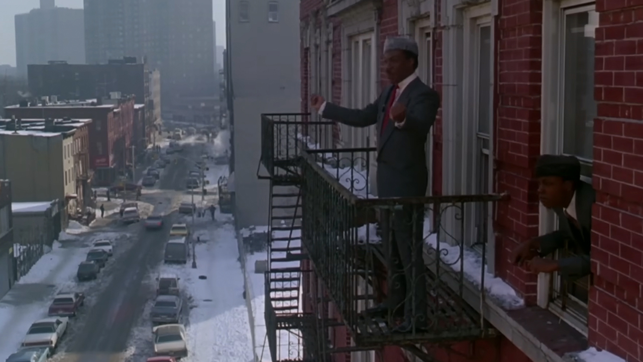 Eddie Murphy standing on a balcony in a cold, snowy New York in Coming To America.