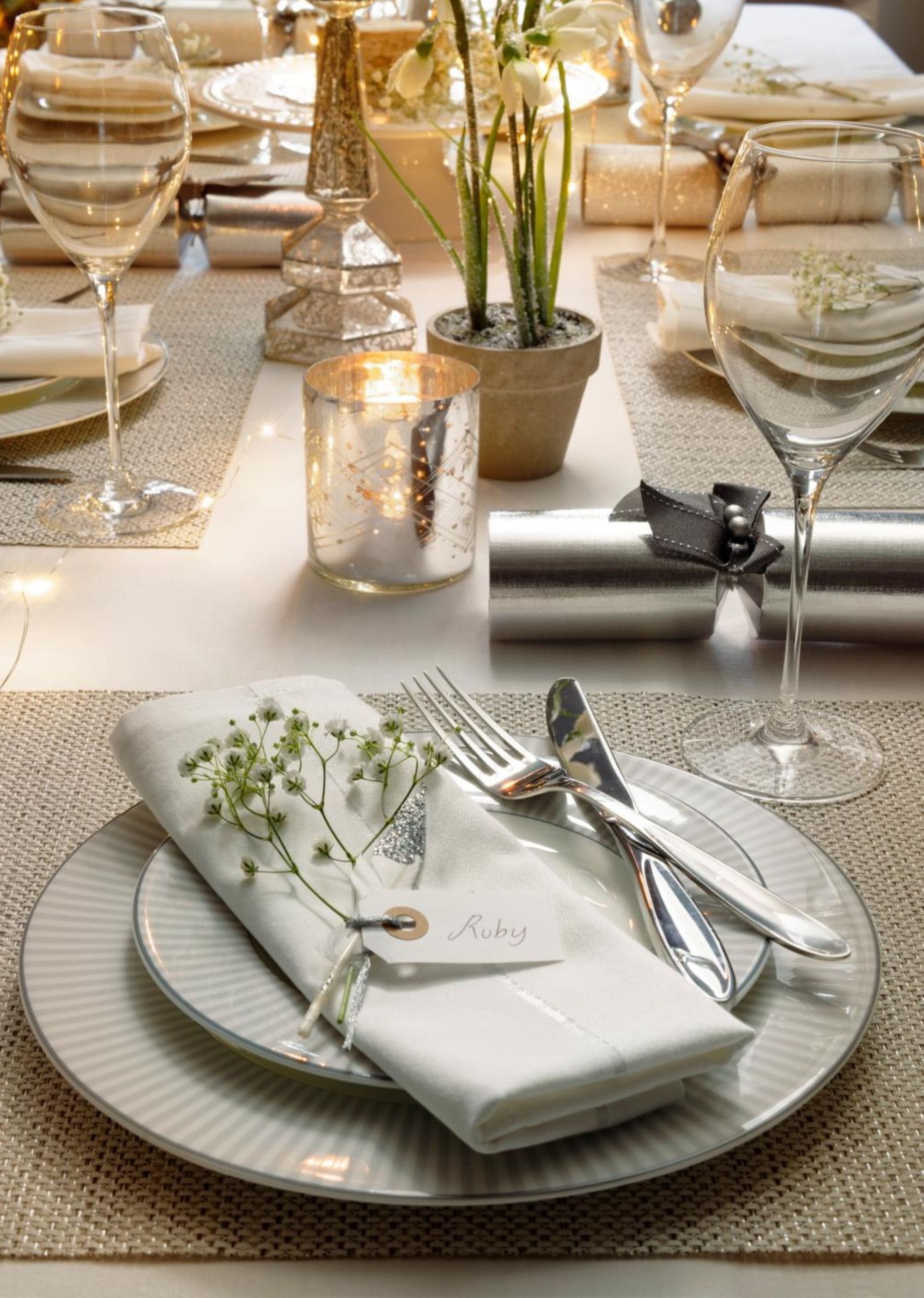 table setting with a large plate and a small salad plate stacked, on top rests a white napkin, silver cutlery, and a wine glass