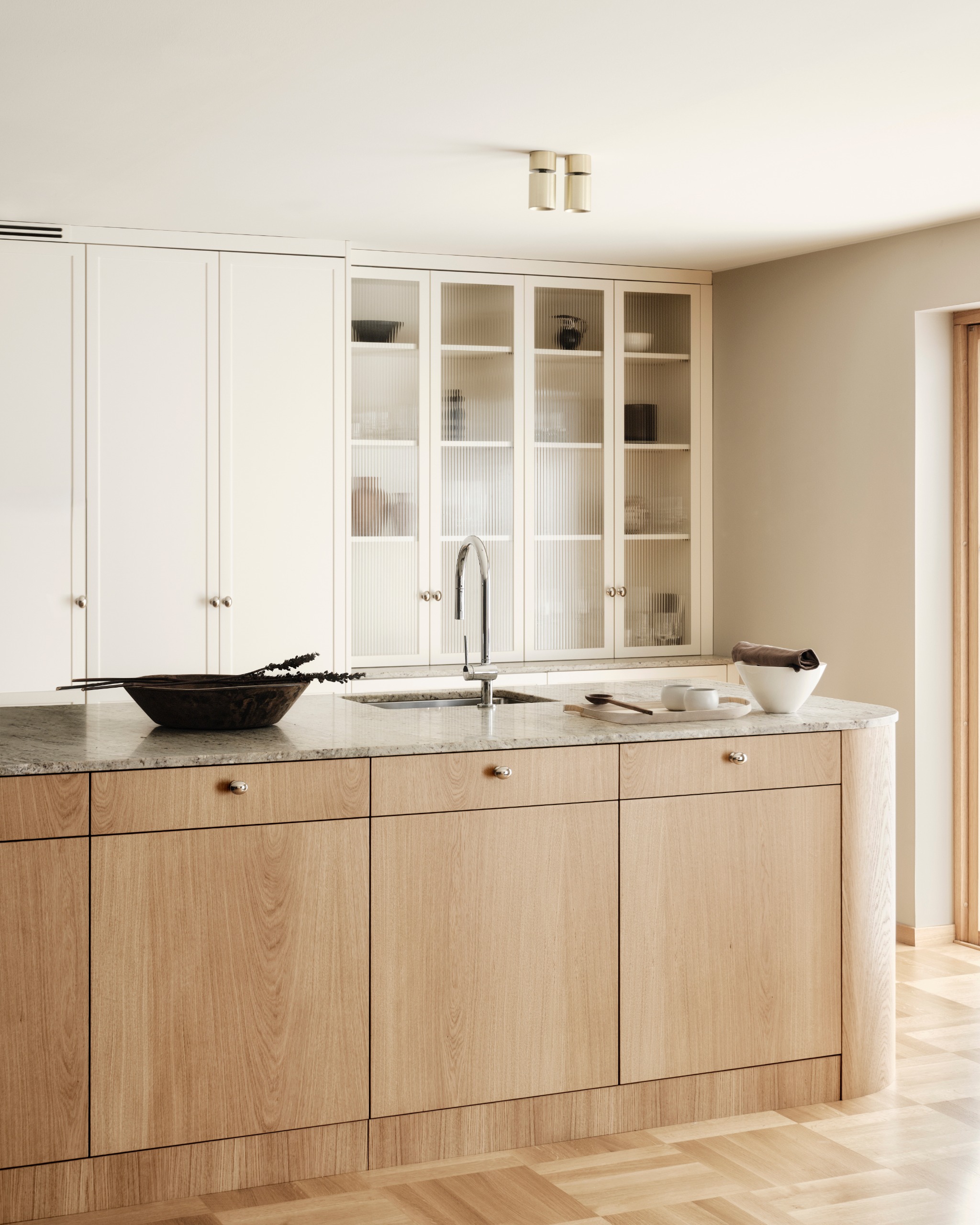 A sleek minimalist kitchen in wood and white withe a curved island