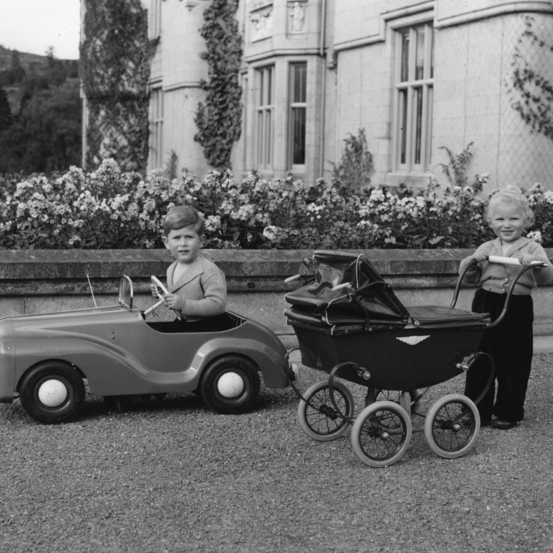 King Charles and Princess Anne playing with a toy car and buggy as kids