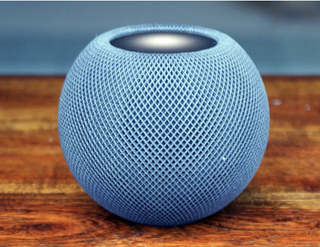 Apple HomePod Mini in blue on a wooden surface