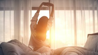 Woman wakes up and stretches in front of the sunrise