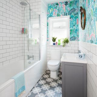 bathroom with colourful wallpaper and brick tile wall bathtub window and commode