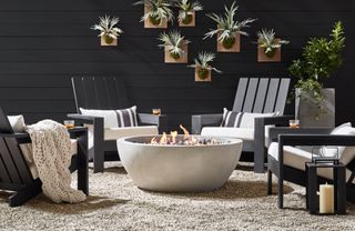 A group of black Adirondack chairs around a fire pit