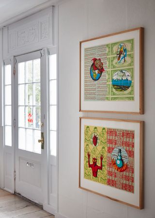 To the right, we see two framed colorful lithographs. The first one has a planet, a brain, and a nature shot, on the background of music notes and dollar bills. The second one has a heart, the devil, and a snowman on the background of colorful posters.