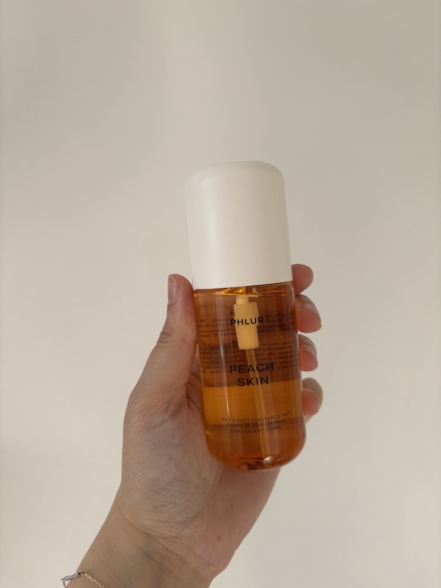Mica Ricketts holding Phlur Peach Skin Body Mist