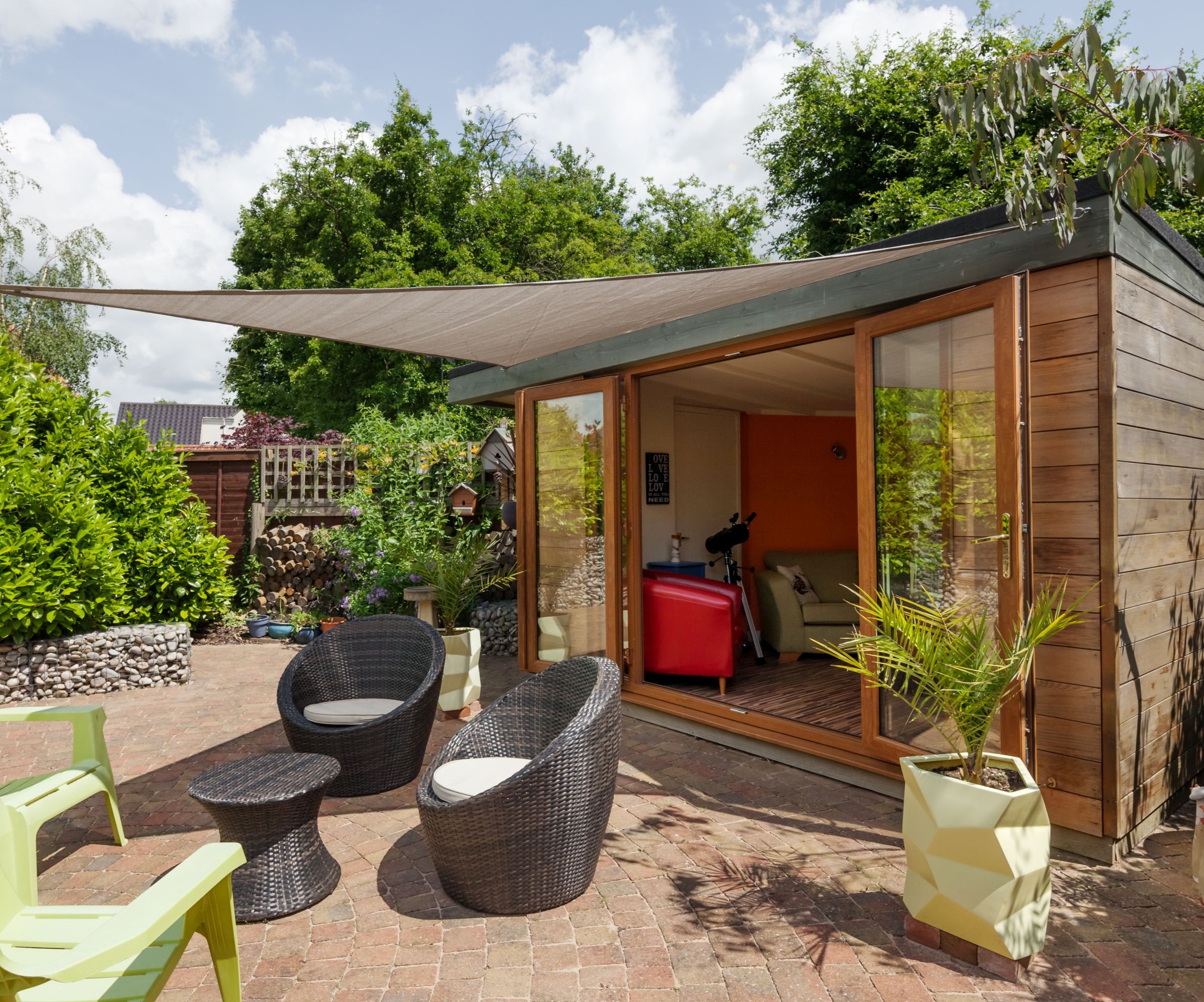 A garden officer with timber cladding and a patio out front and sliding glass doors