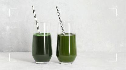 Two glasses of greens powder in water sat side by side on a concrete counter, to represent the question are greens powders a waste of money