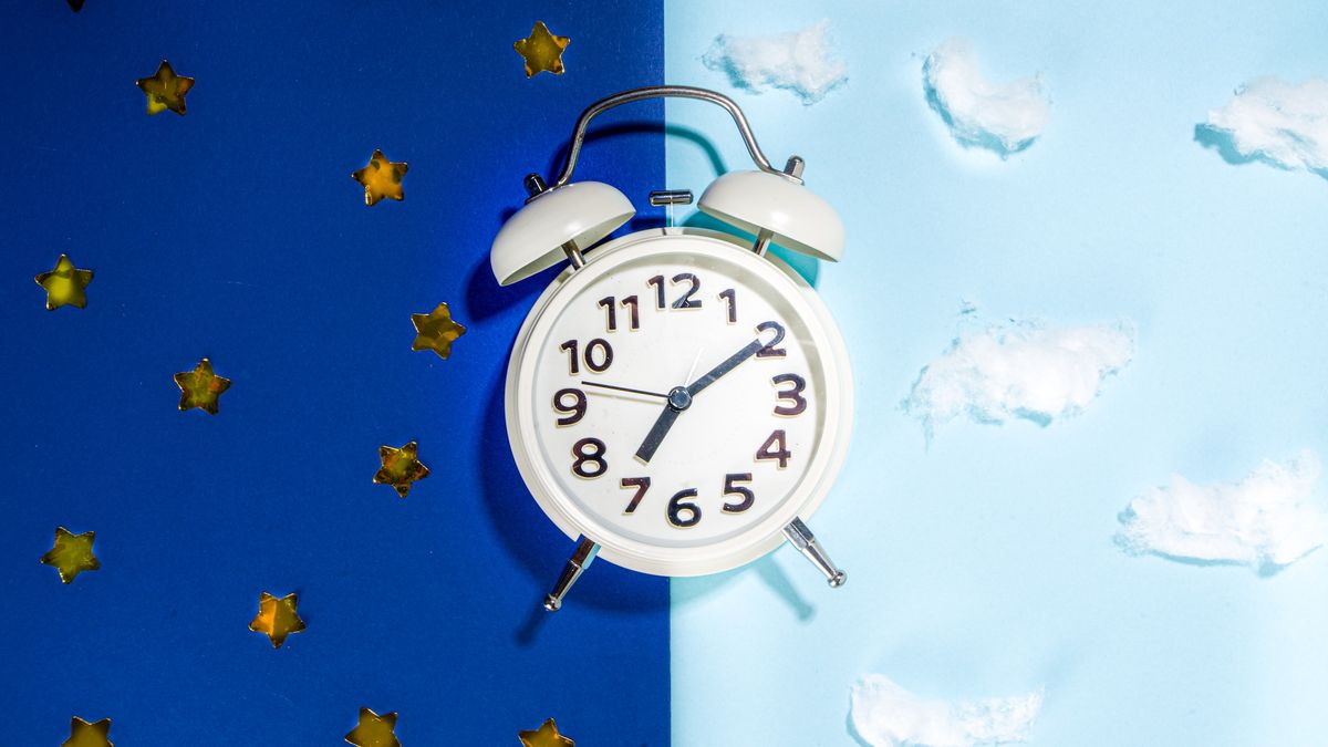 An analog alarm clock on a split background, with the left side representing a night sky and the right side representing a daytime sky