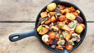 Black cast iron skillet pan with vegetables roasting