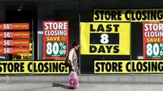 A pedestrian walks past a shop with a closing down sale promotion in Liverpool