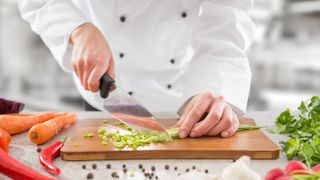 A chef preparing vegetables with a chef's knife