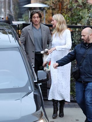 Gwyneth Paltrow wearing a white sweater dress with slouchy black boots