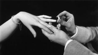 Man placing engagement ring on woman's hand