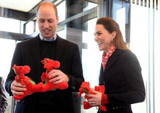 Prince William, Duke of Cambridge and Catherine, Duchess of Cambridge react, holding dragon toys they received for their children