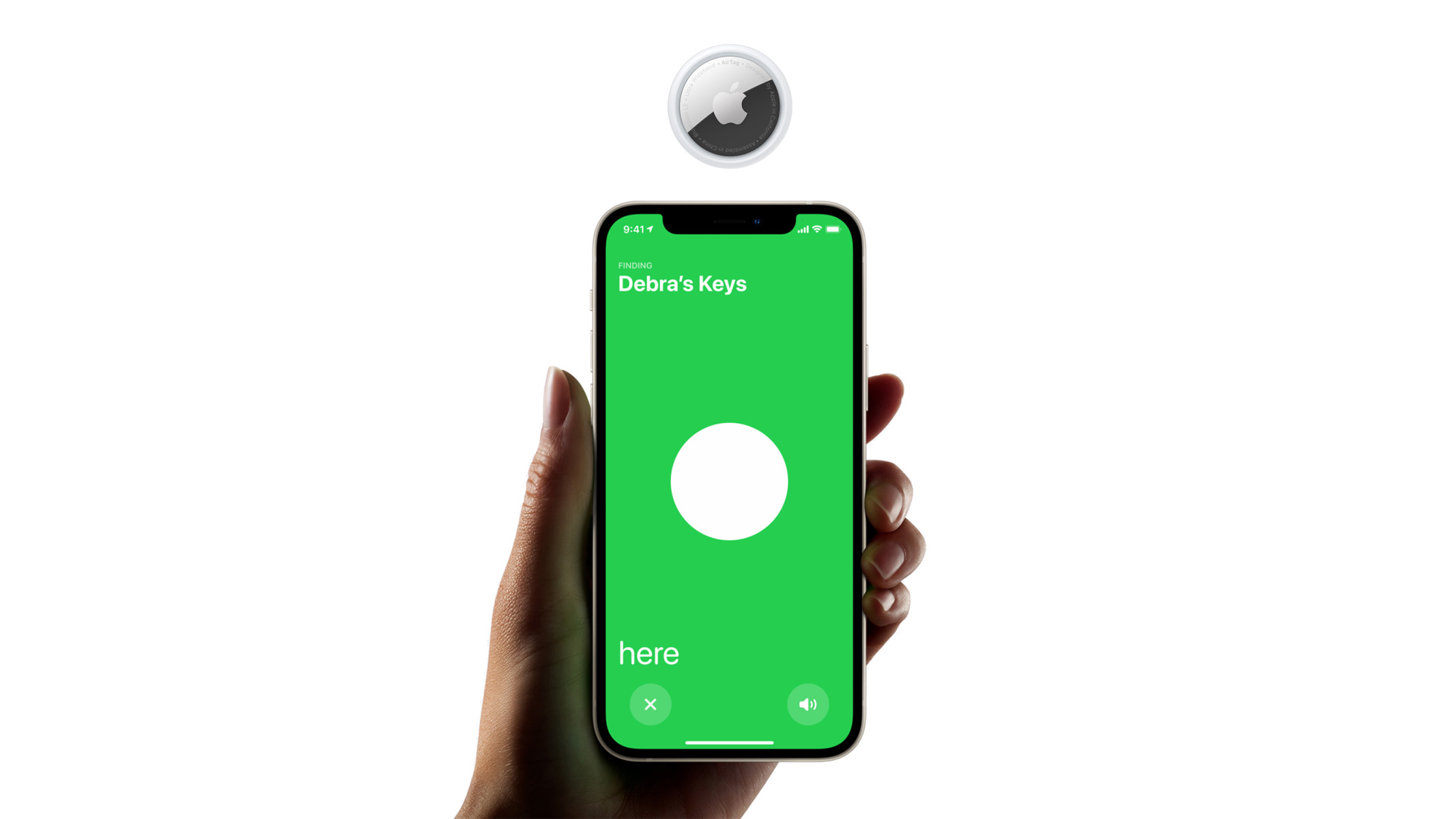 An Apple Airtag floating above a phone, being held by a hand.