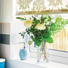 glass vase with yellow flower and roller blind