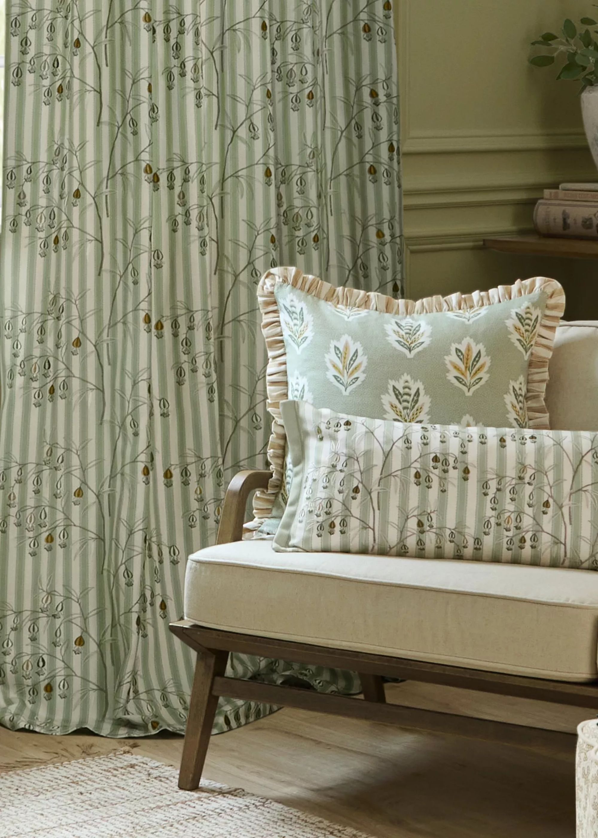Patterned curtains hanging next to an accent chair that has two patterned cushions on top