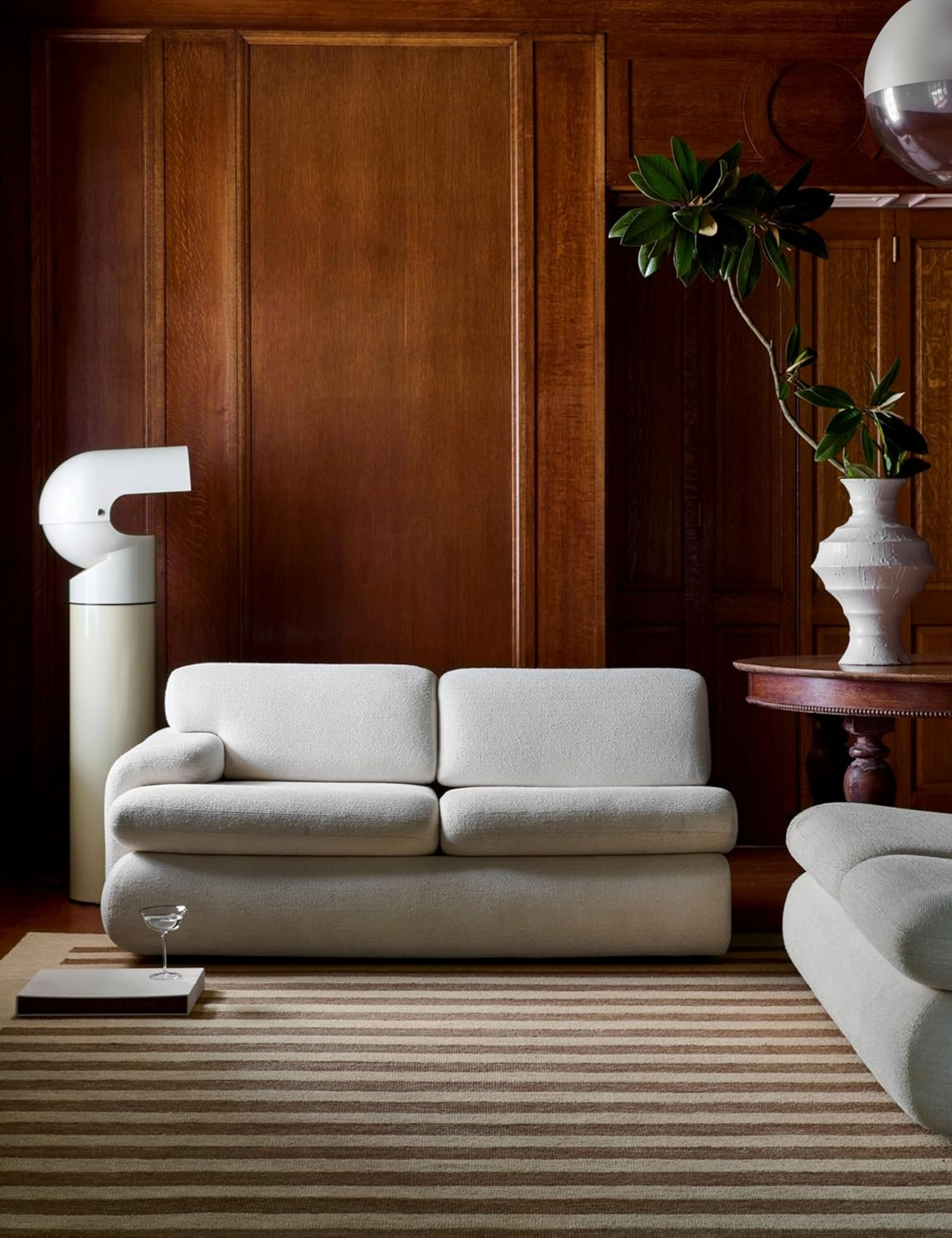 Wood-paneled living room with decorative millwork anchored by a neutral striped area rug