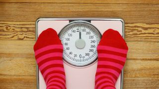 A person weighing themselves with bathroom scales